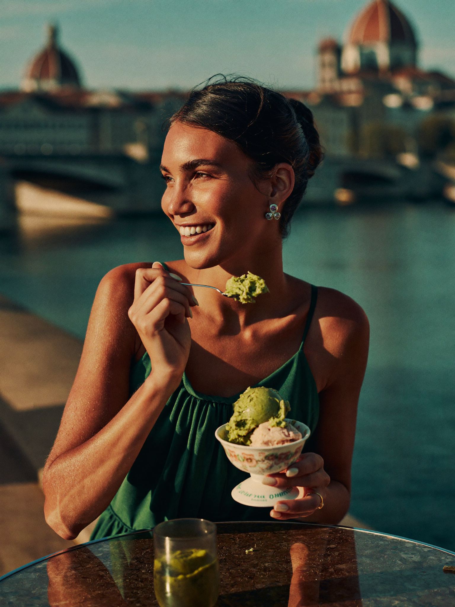 Frau geniesst Pistazien-Gelato am Fluss bei Sonnenuntergang
